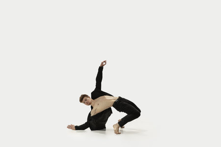 Man in casual style clothes jumping and dancing isolated on white background. Art, motion, action, flexibility, inspiration concept. Flexible caucasian ballet dancer.の写真素材