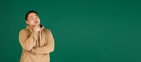 Asian mans portrait isolated over green studio background with copyspace