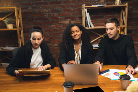 Colleagues working together in modern office using devices and gadgets during creative meeting