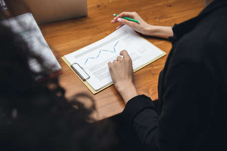 Close up hands of people, managers working in modern office using modern devices and flipchart with...