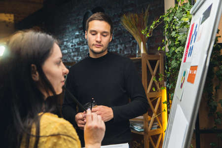 Colleagues working together in modern office using flipchart during creative meeting