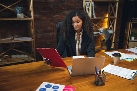 Young woman working in modern office using devices and gadgets. Making reports, analitycs, routine...