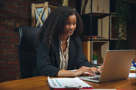 Young woman working in modern office using devices and gadgets. Making reports, analitycs, routine...