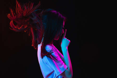 Asian young womans portrait on dark studio background in neon. Concept of human emotions, facial...