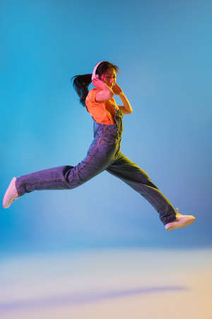 Asian young womans portrait on blue studio background in neon. Concept of human emotions, facial...