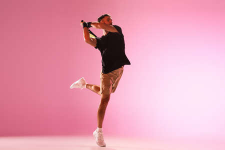 Young caucasian man playing tennis isolated on pink studio background, action and motion conceptの写真素材