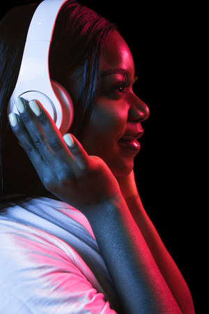 African young womans portrait on dark studio background in neon. Concept of human emotions, facial...