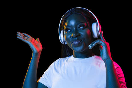 African young womans portrait on dark studio background in neon. Concept of human emotions, facial...