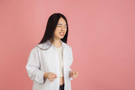 Asian young womans portrait on pink studio background. Concept of human emotions, facial expression,...