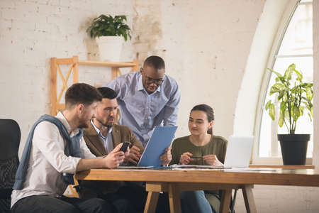 Colleagues working together in modern office using devices and gadgets during creative meeting