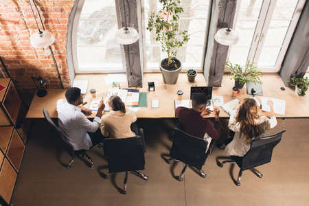 Colleagues working together in modern office using devices and gadgets during negotiations. Top...