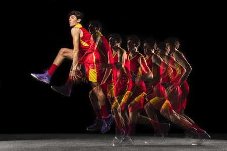 Young caucasian basketball player in motion and action in mixed light on dark background. Concept of...
