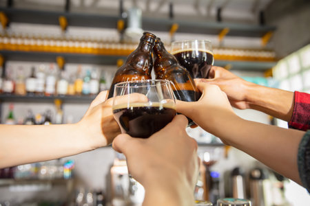 Close up hands clinking glasses and bottles with beer. Emotional fans cheering for favourite team, watching on exciting game. Concept of friendship, leisure activity, emotionsの写真素材
