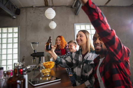 Group of friends watching sport match together. Emotional fans cheering for favourite team, watching on exciting game. Concept of friendship, leisure activity, emotionsの写真素材