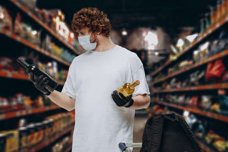 Young Caucasian man buyer wearing face protective mask during the shopping. Healthy lifestyle conceptの写真素材