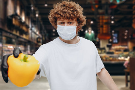 Close-up young Caucasian man buyer wearing face protective mask during the shopping. Healthy lifestyle conceptの写真素材