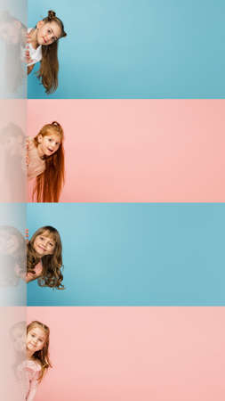 Four happy little girls looking at camera isolated over bicolored studio background. Creative...