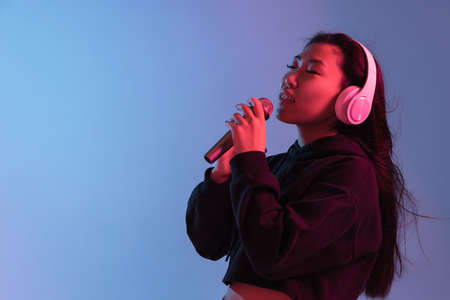 Asian young womans portrait on gradient colors studio background in neon. Concept of human emotions.の写真素材