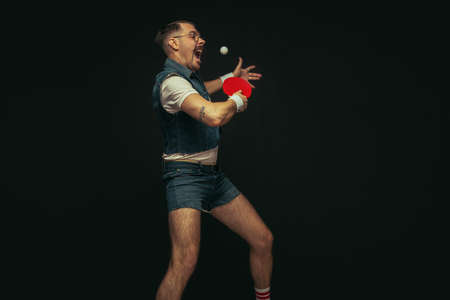 Young caucasian man playing tennis isolated on black studio background in retro style, action and motion conceptの写真素材