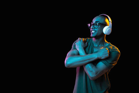 African-american young mans portrait on dark studio background in neon. Concept of human emotions,...