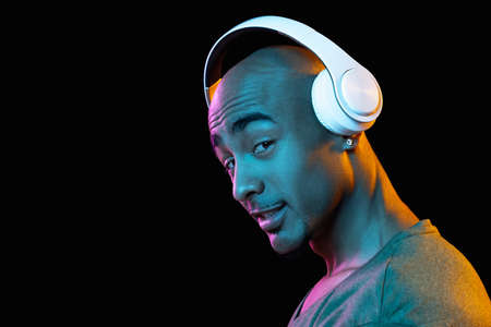 African-american young mans portrait on dark studio background in neon. Concept of human emotions,...
