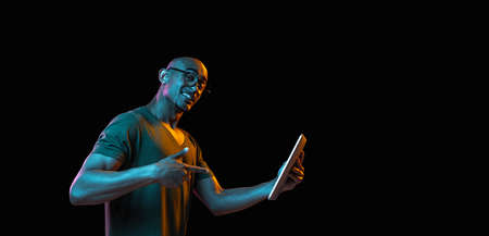African-american young mans portrait on dark studio background in neon. Concept of human emotions,...