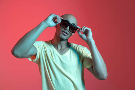 African-american young mans portrait on red studio background in neon. Concept of human emotions, facial expression, youth, sales, ad.の写真素材