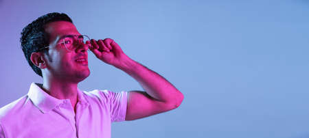 Latina young mans portrait on purple-blue studio background in neon. Concept of human emotions,...