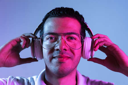 Latina young mans portrait on purple-blue studio background in neon. Concept of human emotions,...