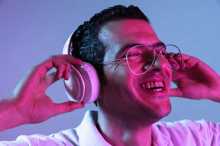 Latina young mans portrait on purple-blue studio background in neon. Concept of human emotions, facial expression, youth, sales, ad.の写真素材