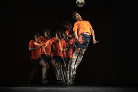Young male football soccer player in motion and action in mixed light on dark background.の写真素材