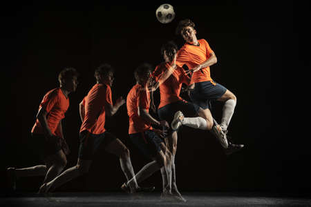 Young male football soccer player in motion and action in mixed light on dark background.の写真素材