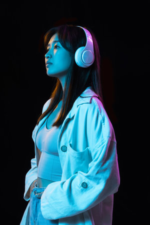 Asian young womans portrait on dark studio background in neon. Concept of human emotions, facial expression, youth, sales, ad.の写真素材