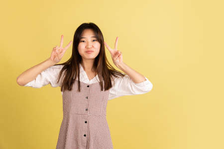 Asian young womans portrait on yellow studio background. Concept of human emotions, facial expression, youth, sales, ad.の写真素材