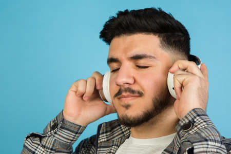 Young mans portrait on blue studio background. Concept of human emotions, facial expression, youth,...