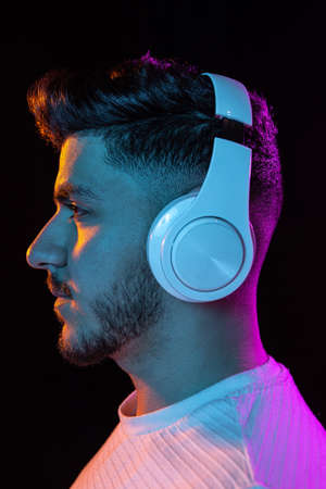 Young mans portrait on black studio background in neon light. Concept of human emotions, facial...