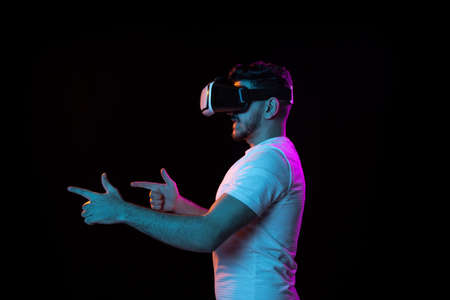 Young mans portrait on black studio background in neon light. Concept of human emotions, facial expression, youth, sales, ad.の写真素材