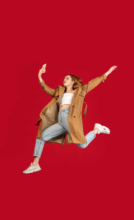 Young happy girl jumping isolated over red studio background with copyspace for ad. Concept of...