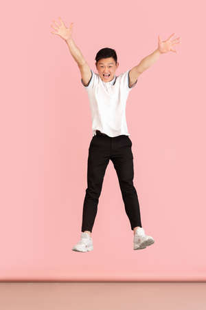 Full-length portrait of Asian young man isolated on pink studio background. Concept of human emotionsの写真素材