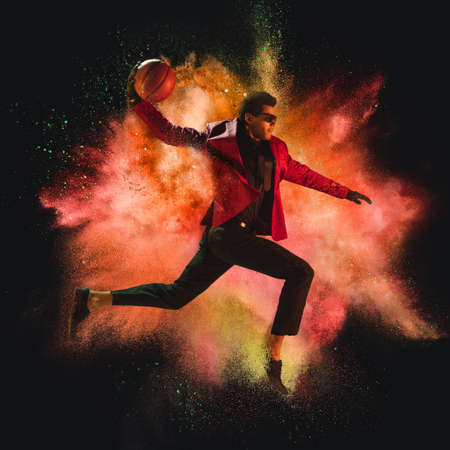 One young sportsman basketball player in explosion of colored neon powder isolated on dark...