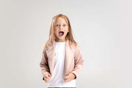 Beautiful little girl looking suprised on pastel studio backgroundの写真素材