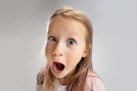 Beautiful little girl looking suprised on pastel studio backgroundの写真素材