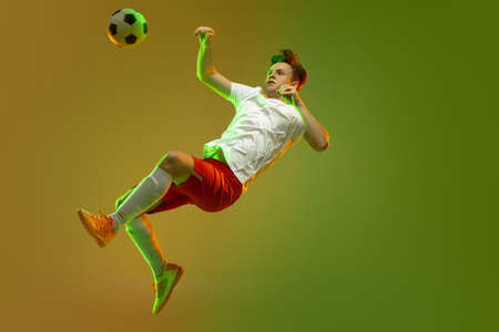 Young caucasian man, male soccer football player training isolated on gradient yellow green background in neon lightの写真素材