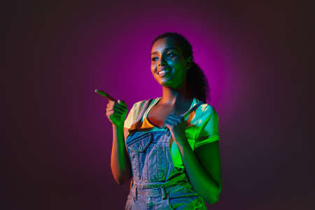 Latino young womans portrait on dark studio background in neon. Concept of human emotions, facial expression.の写真素材