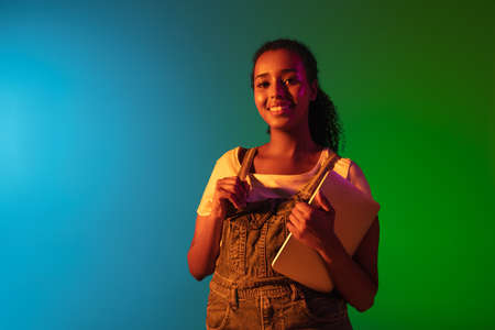 Latino young womans portrait on dark studio background in neon. Concept of human emotions, facial expression.の写真素材
