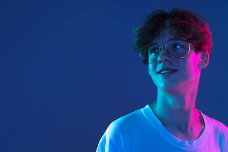 Caucasian young mans portrait on dark studio background in neon. Concept of human emotions, facial expression.の写真素材