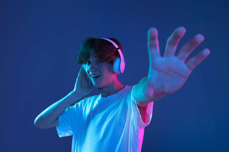 Caucasian young mans portrait on dark studio background in neon. Concept of human emotions, facial...