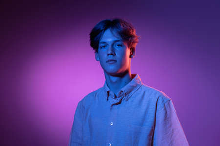 Serious. Handsome caucasian mans portrait isolated on purple studio background in neon, monochrome. Beautiful male model.の写真素材