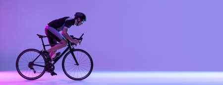 Cyclist riding a bicycle isolated against neon backgroundの写真素材