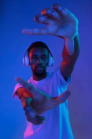 African-american young mans portrait on red studio background in neon. Concept of human emotions, facial expression, youth, sales, ad.の写真素材